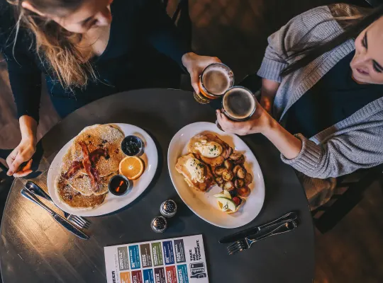 A top down of food with people enjoying companyand beers